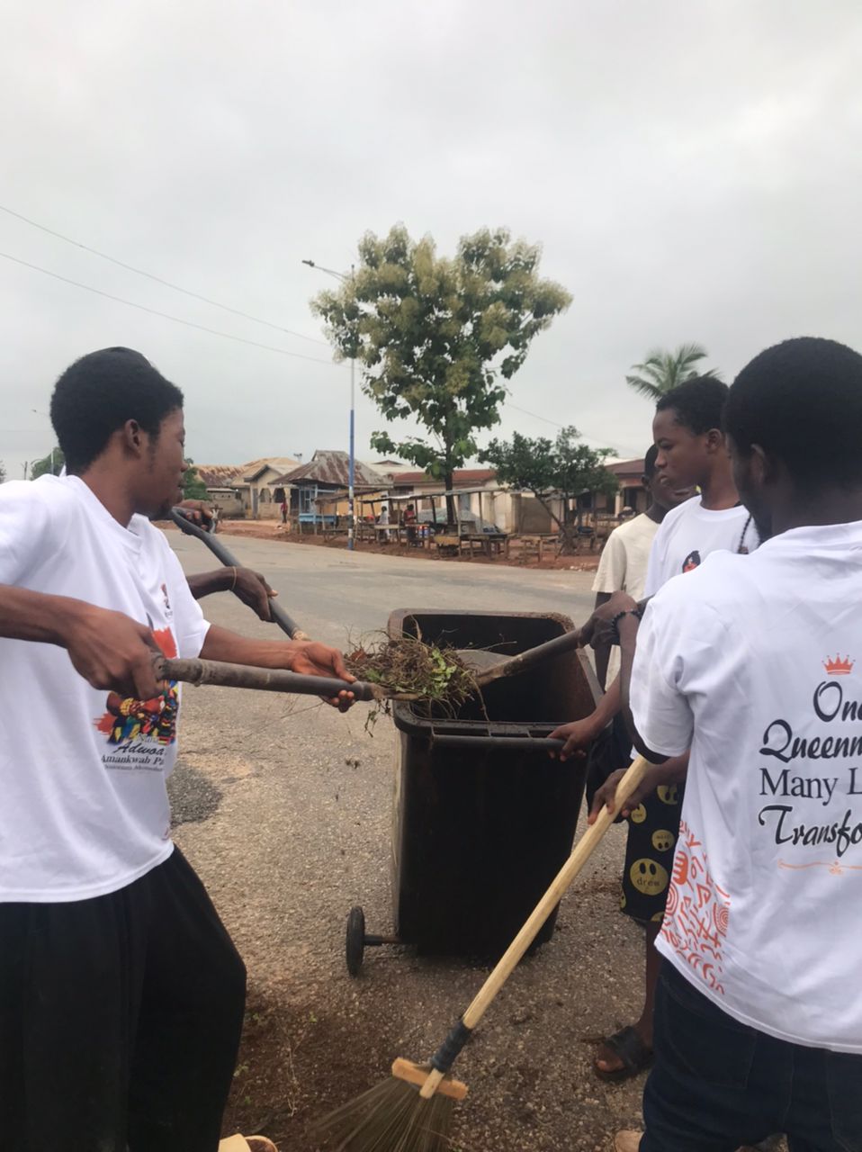 Young volunteers in Queennaap t-shirts walking through the community with brooms